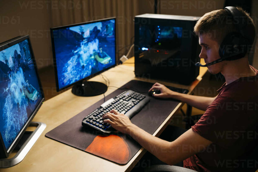 young man playing video games with computer at desk JRFF04793