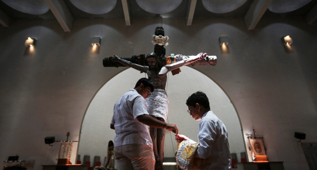 Two boys prepare a statue of Jesus Christ after a procession on Good Friday in the Holy Week celebra